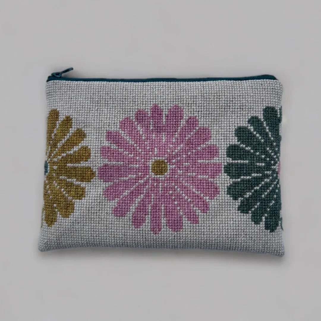 Broderet clutch med tre store blomster i olivengrøn, rosa og mørk grøn på lys stramaj, med petroleumsfarvet lynlås