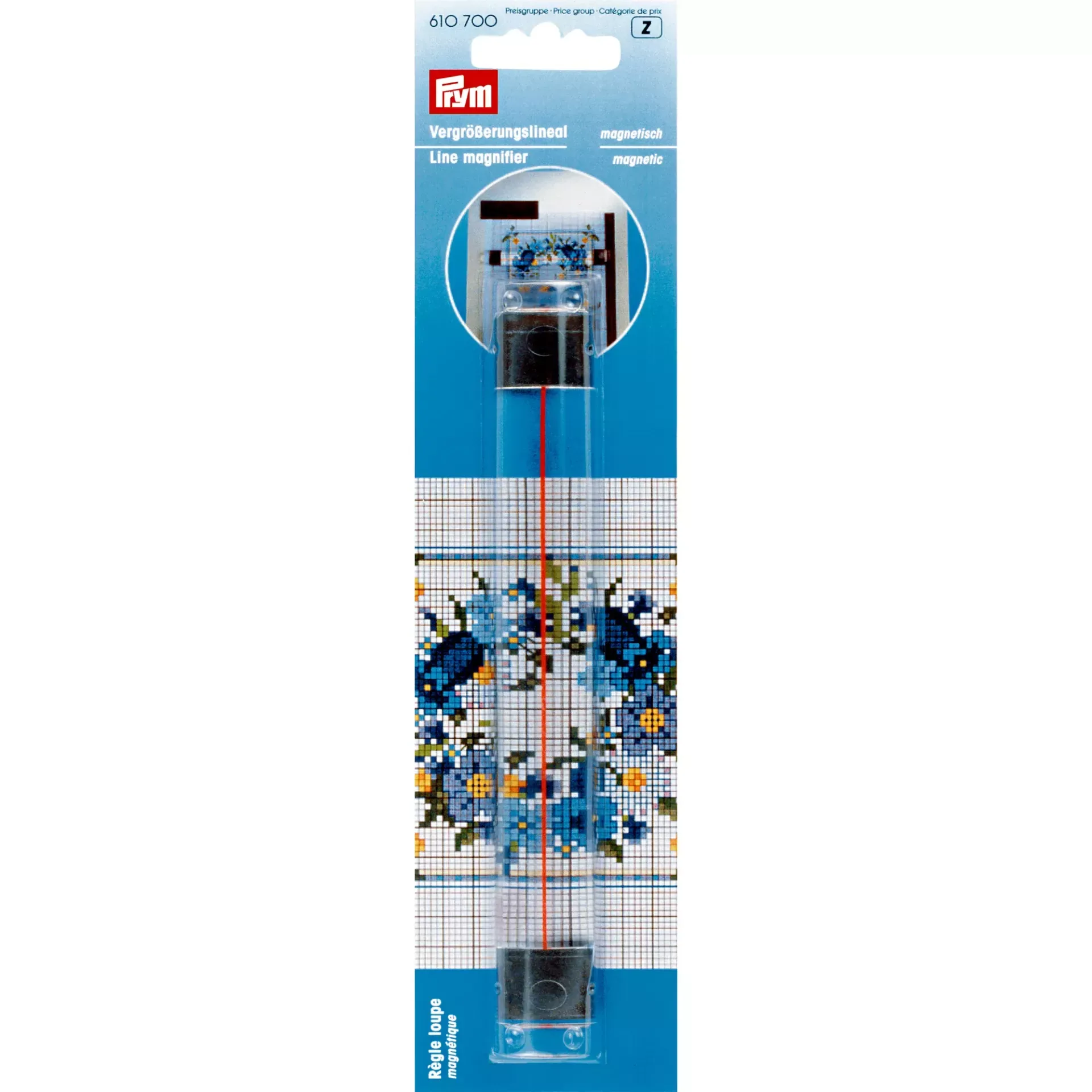 Prym lup-lineal i emballagen, vist hen over et korsstingsdiagram med blå blomster